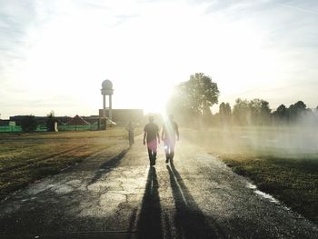 Rear view of people walking on road against sky