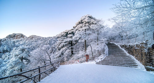 Snow covered footbridge against clear sky