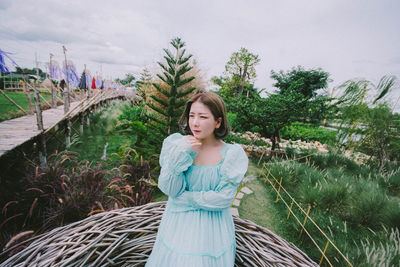 Woman standing by tree against sky
