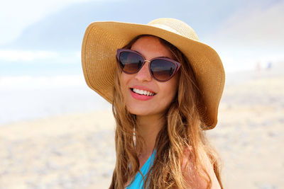 Portrait of smiling woman wearing sunglasses at beach