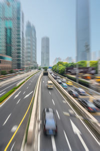 Blurred motion of vehicles on road against buildings in city