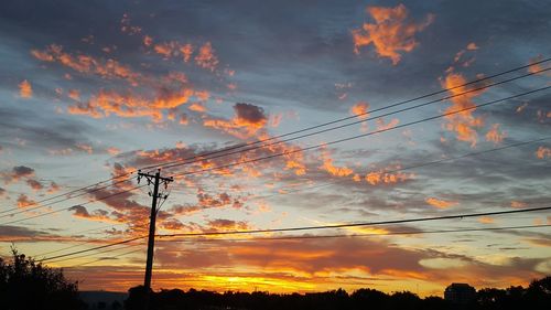 Low angle view of electricity pylon against dramatic sky