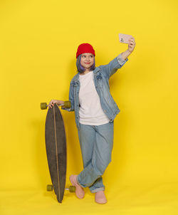 Portrait of young woman standing against yellow background
