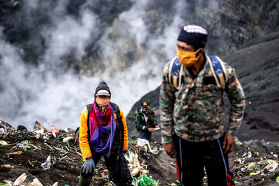 People on rocks against mountains during winter