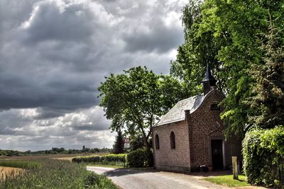 Road by chapel against cloudy sky