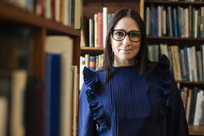 Portrait of smiling woman standing in library