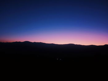 Scenic view of silhouette mountains against clear sky at sunset