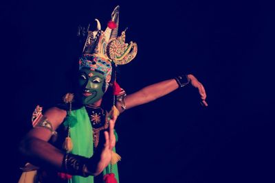 Low angle view of woman dancing against black background