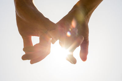 Close-up of hands against sky over white background