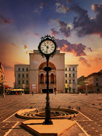 Clock tower against buildings in city at sunset