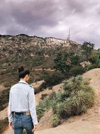 Rear view of man standing on mountain against sky