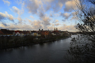 Scenic view of river by buildings against sky