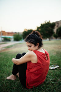 Young woman looking away while sitting on land