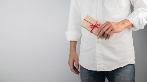 Midsection of man holding umbrella standing against white background