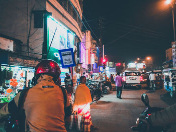 Rear view of people on city street at night