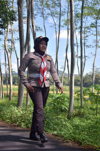 Full length portrait of young man standing against trees