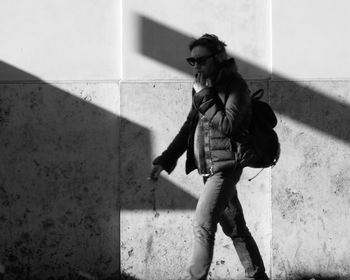 Full length of young woman standing against wall
