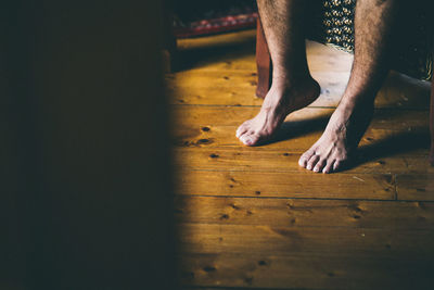 Low section of man relaxing on hardwood floor