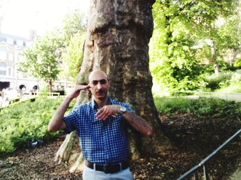Portrait of smiling young man standing on tree trunk