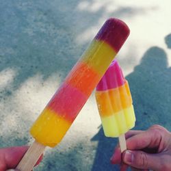 Cropped hands holding flavored ice on road