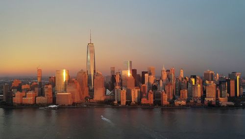 River in front of city against clear sky during sunset