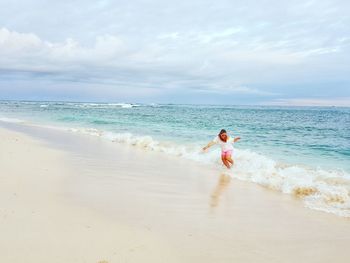 Woman standing on beach against sky