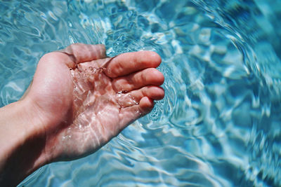 Close-up of person hand on wet swimming pool