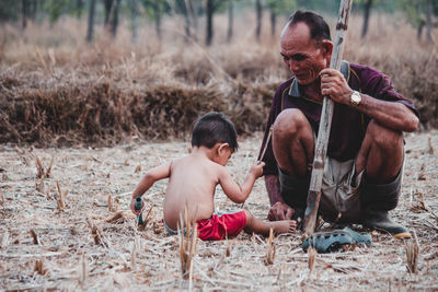 Grandfather and grandson sitting on field