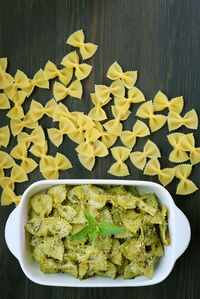 Bowl of homemade farfalle pasta with pesto sauce on wooden table