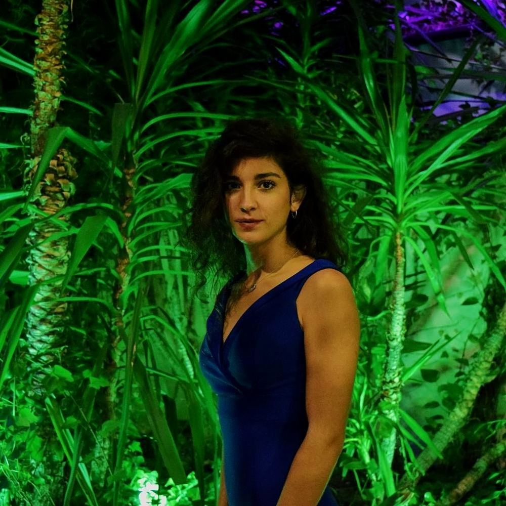 PORTRAIT OF YOUNG WOMAN STANDING AGAINST PLANTS