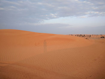 Scenic view of desert against cloudy sky