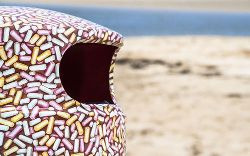 Close-up of garbage can at sandy beach