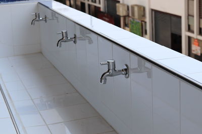 Some metal faucet on white tile sink