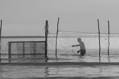 Reflection of silhouette man in swimming pool against sea