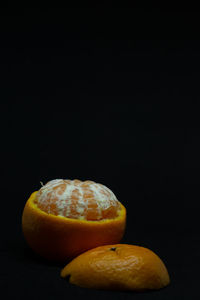 Close-up of orange slice on table against black background