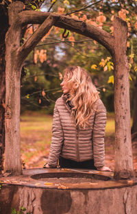 Woman standing by well at park during autumn