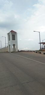 Empty road by building against sky