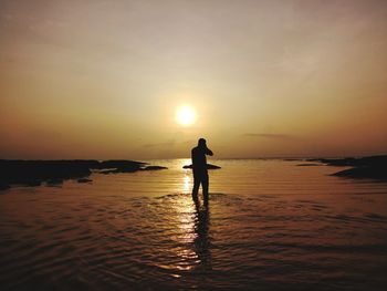 Silhouette man standing on beach against sky during sunset