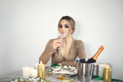 Young woman drinking glass against white background