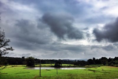 Scenic view of grassy field against cloudy sky