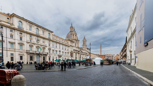 People walking on street in city against sky