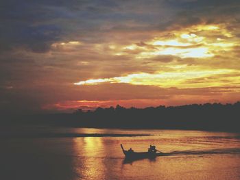 Silhouette man in sea against sky during sunset