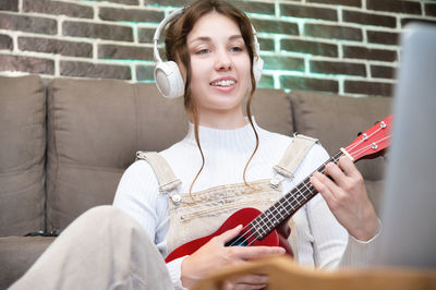 Portrait of young woman playing guitar