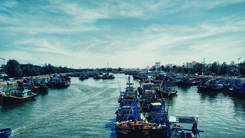 Boats sailing in river against sky in city