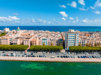 Buildings by sea against sky