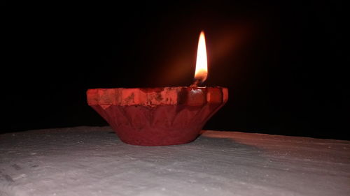 Close-up of illuminated candle in darkroom