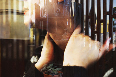 Multiple exposure of woman holding neck and buddha sculpture by fence