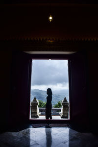 Silhouette woman standing at temple entrance against sky