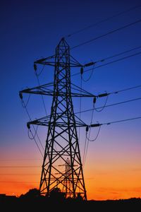 Low angle view of silhouette electricity pylon against sky at sunset