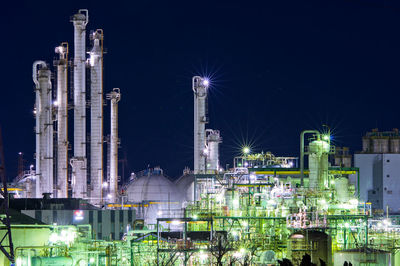 Illuminated factory against sky at night